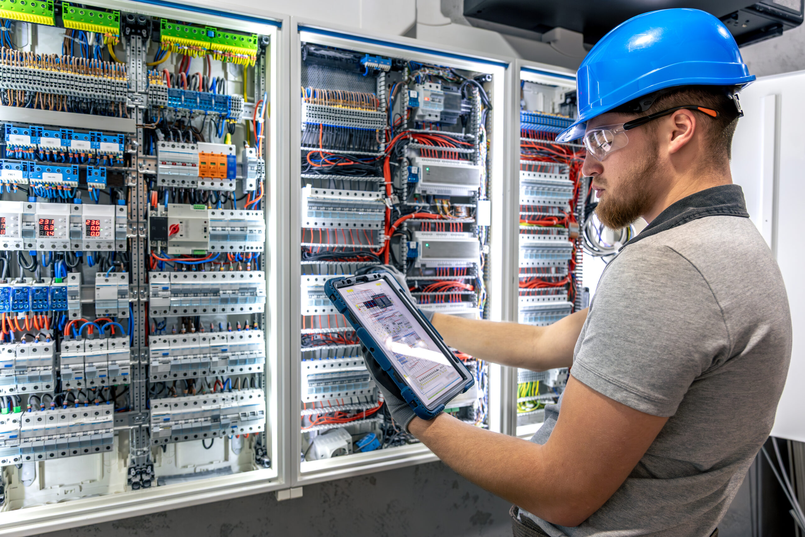Switchboard check. Electrician with tablet. Technology in action.