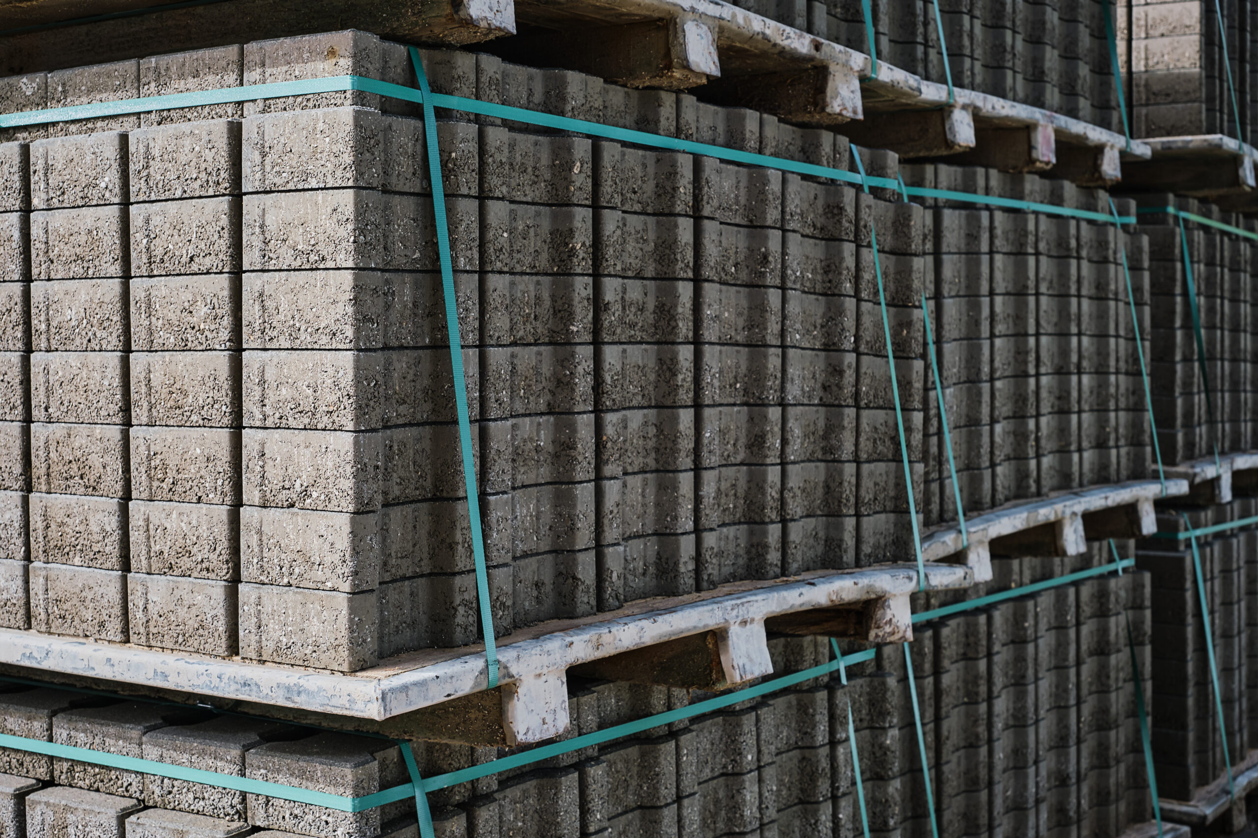 Pallets with stacked gray paving slabs, selective focus. Stack of paving slabs in warehouse, road repair or finished tile sale, space for text